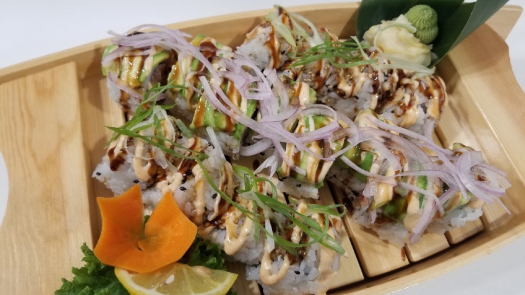 a tray of sushi with onion and avocado