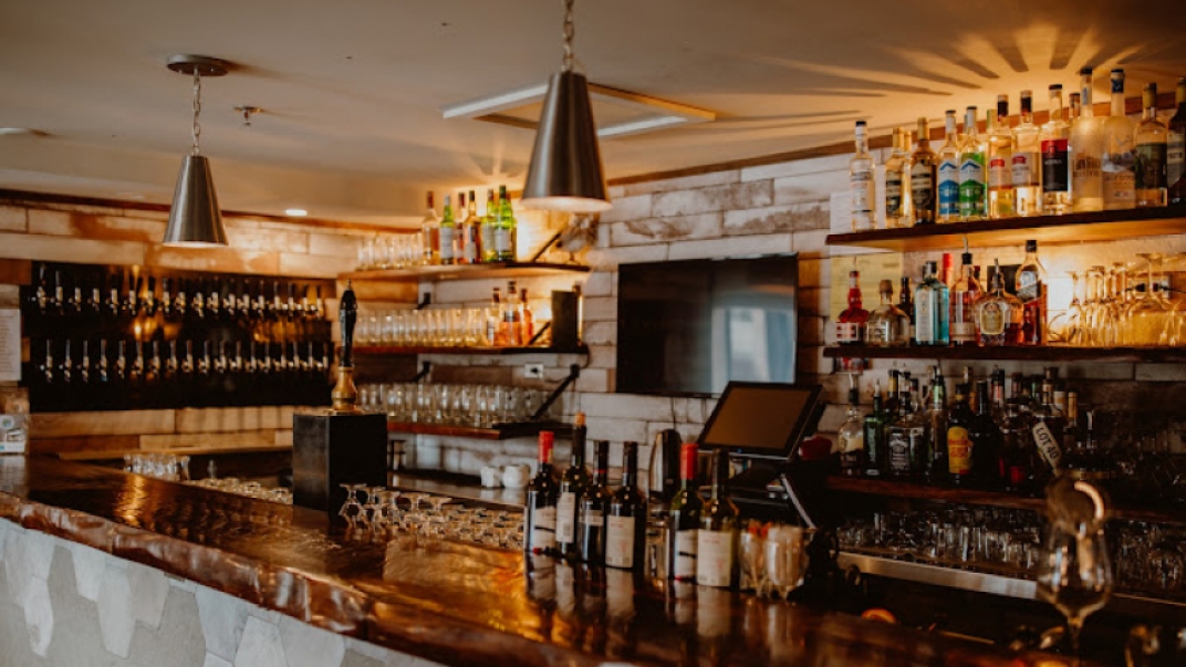 a bar with a wooden counter top and bottles on top