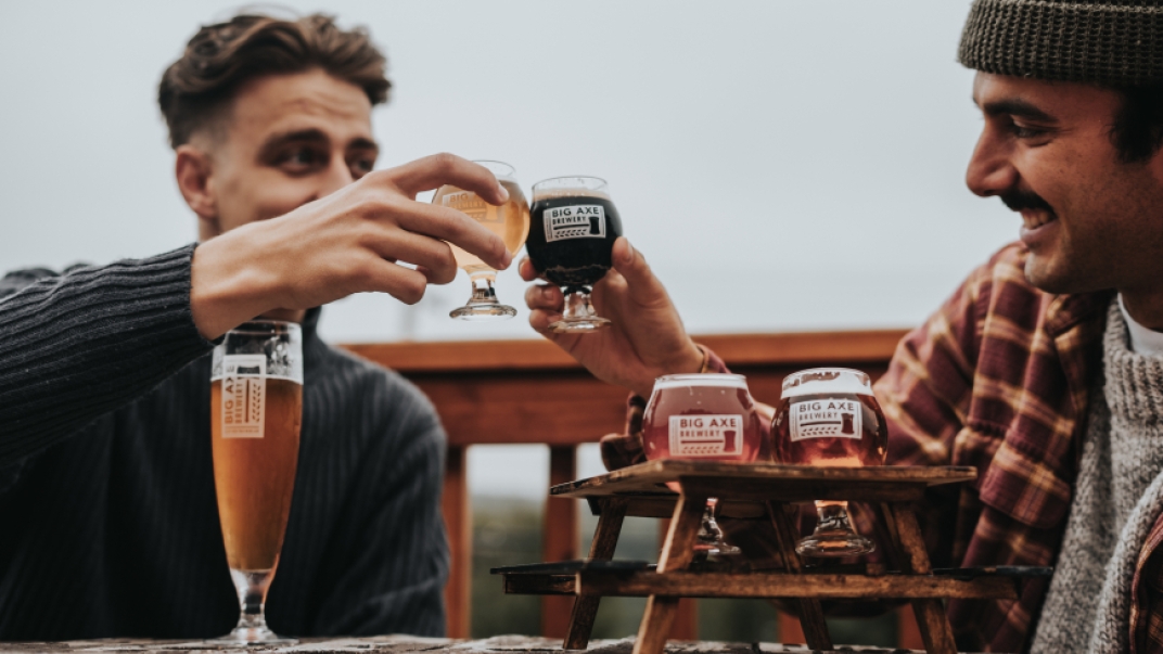 two men holding beers and toasting