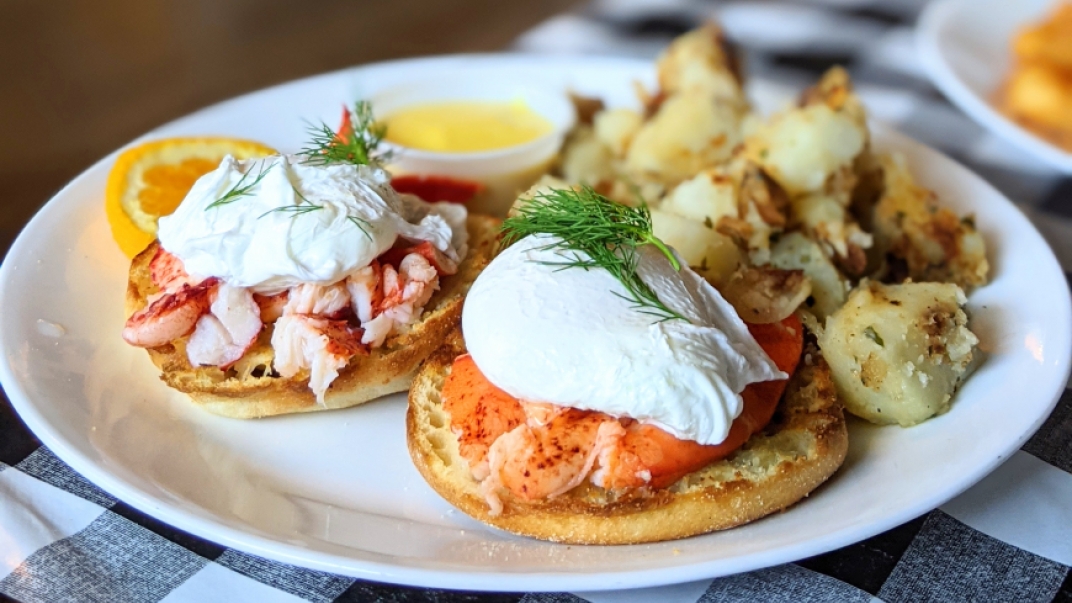 lobster Eggs Benedict with home fries on a white plate