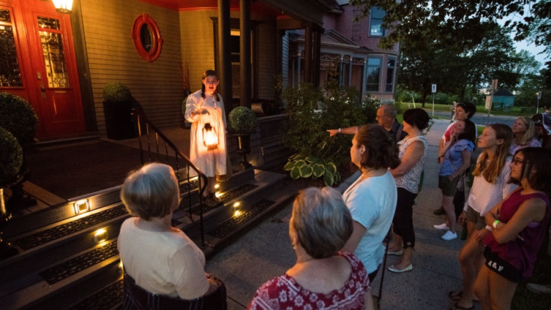 Tour guide holding a lantern narrating haunted stories to a captive audience