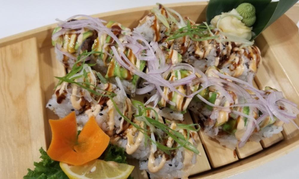 a tray of sushi with onion and avocado