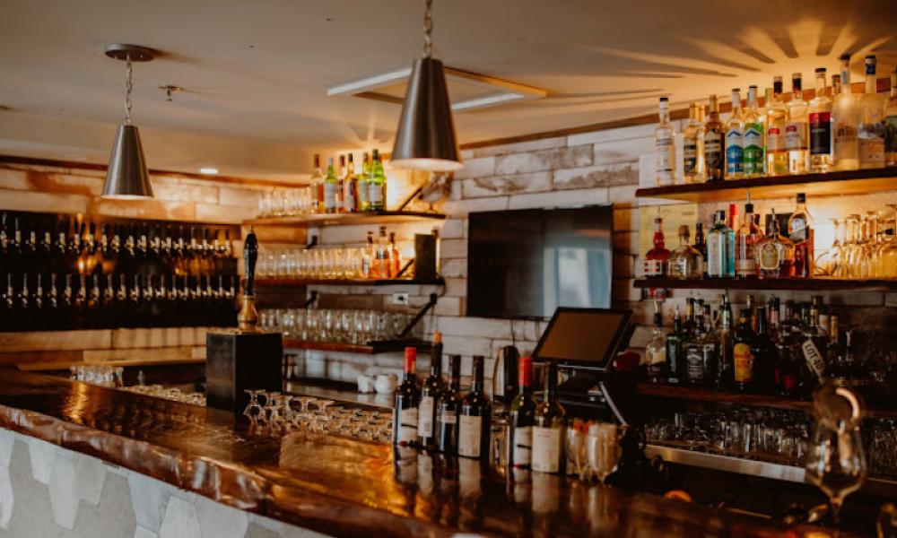 a bar with a wooden counter top and bottles on top
