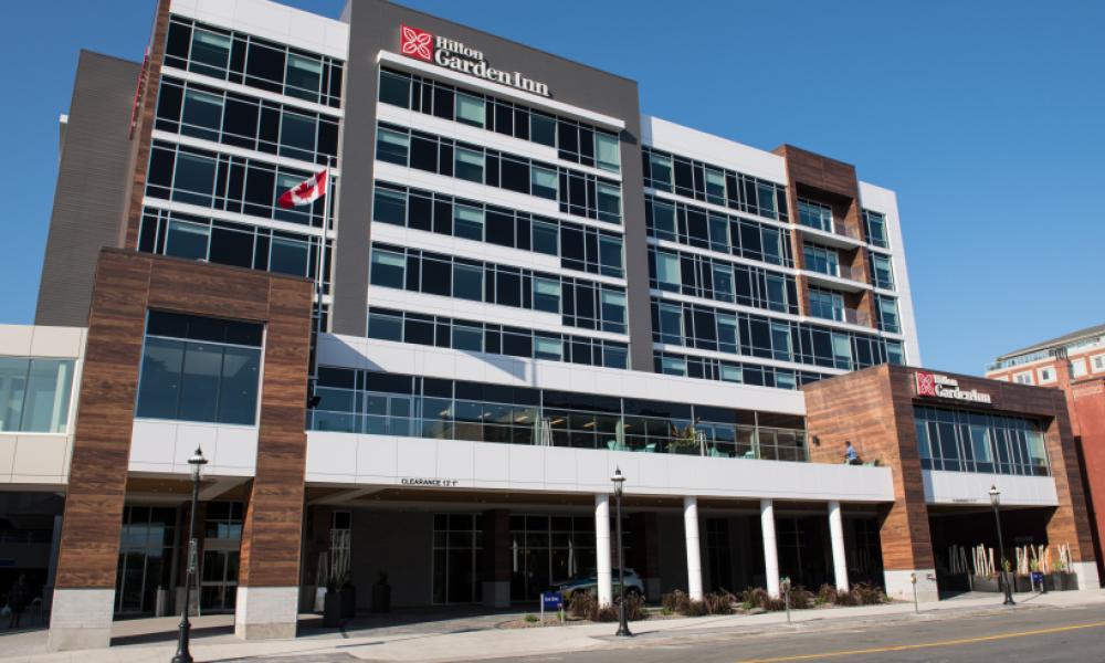 Image of the outside of the Hilton. A brown and white building.