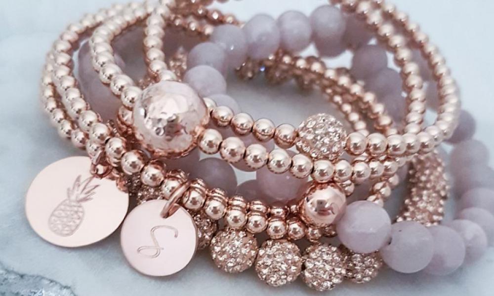 close up shot of rose gold beaded bracelet with a pineapple charm and an S monogram