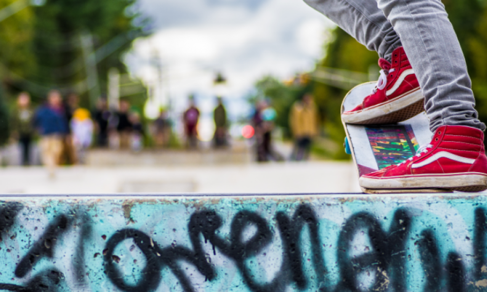 close up shot of a person wearing bright red vans on a skateboard about to drop into the skate bowl