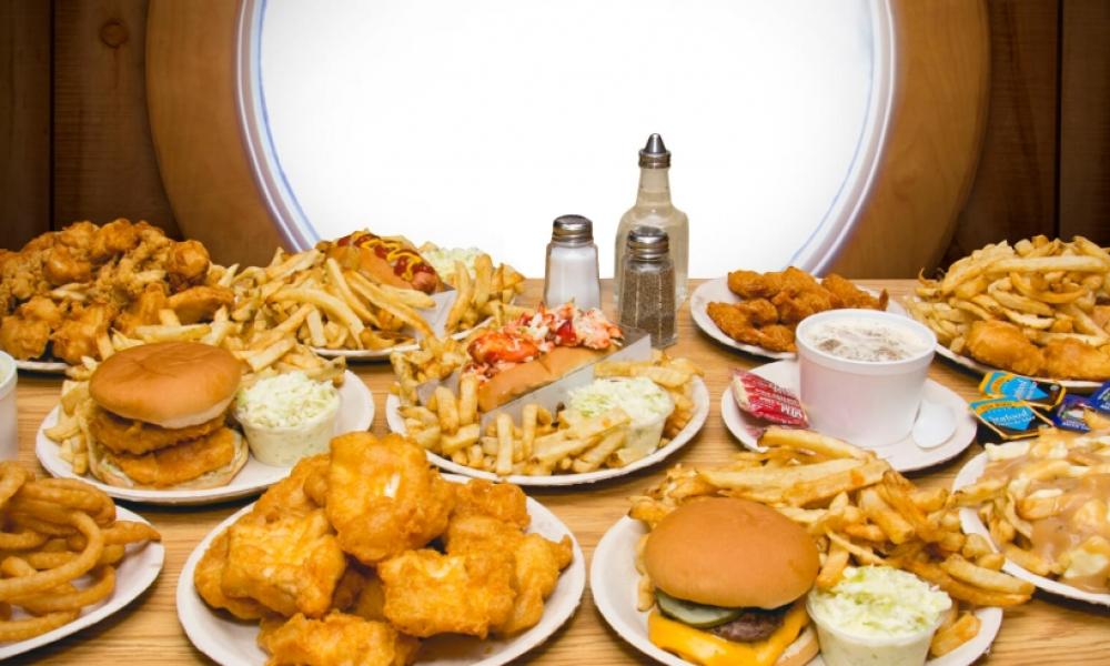 Table full of plates of food including burgers, fries, fish and chips
